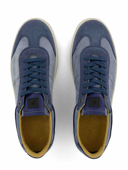 A pair of Rubirosa JUDY Sneakers in Blue Suede, handmade in Italy with tan inner lining, viewed from above on a white background—ideal for sustainable fashion enthusiasts.