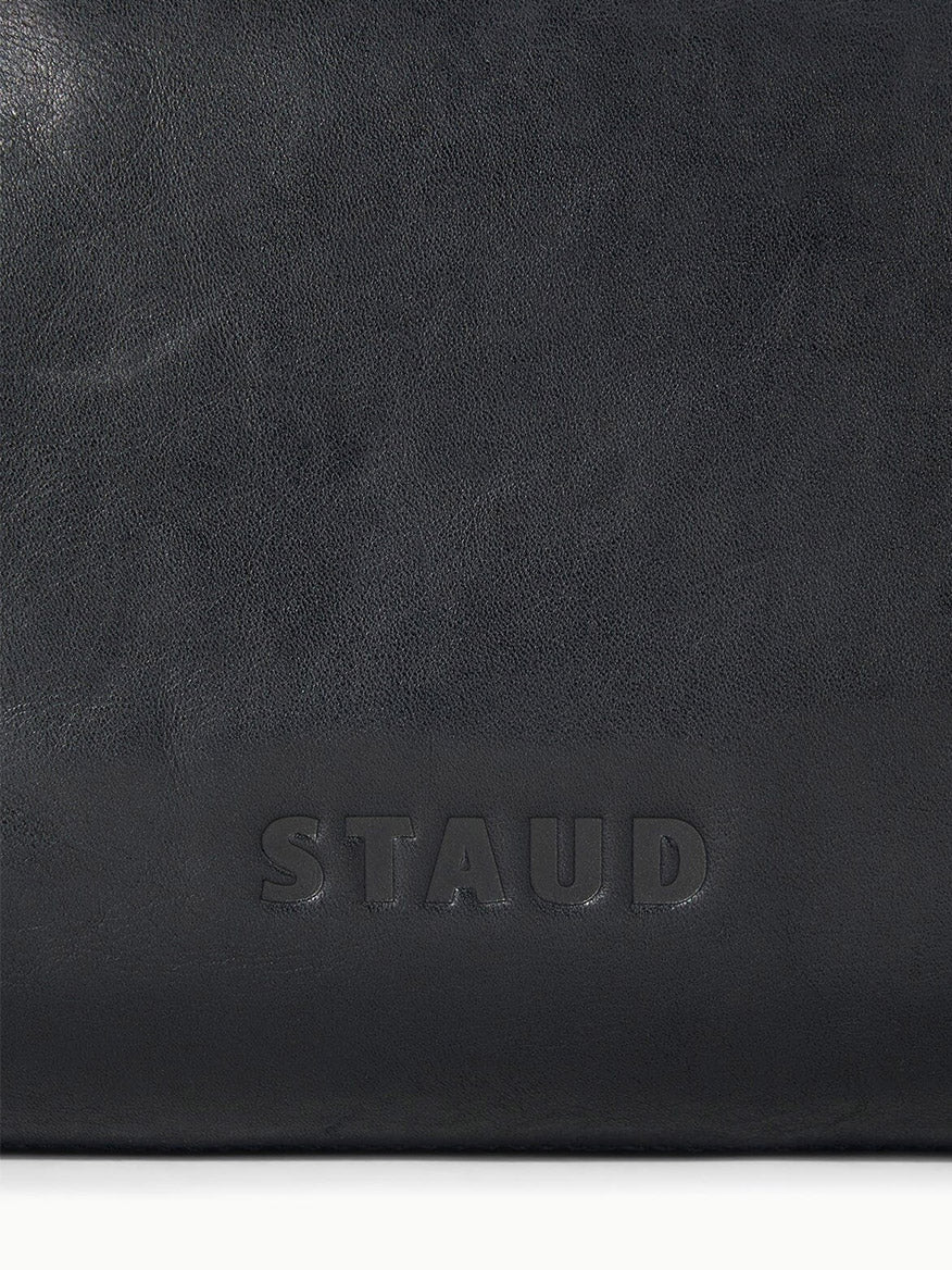 Close-up of a black STAUD Cy Convertible Bag featuring the embossed brand name “STAUD” at the bottom center.
