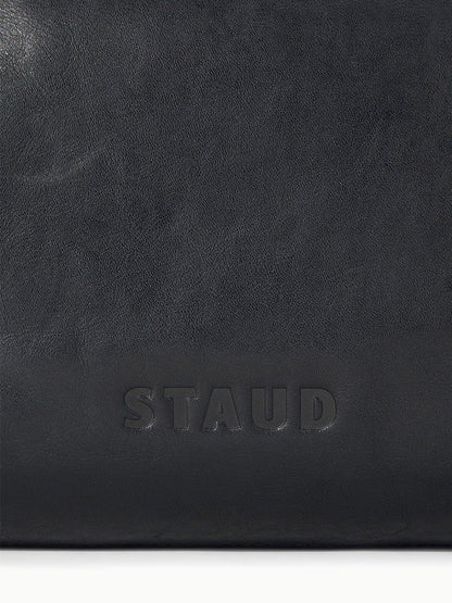 Close-up of a black STAUD Cy Convertible Bag featuring the embossed brand name “STAUD” at the bottom center.