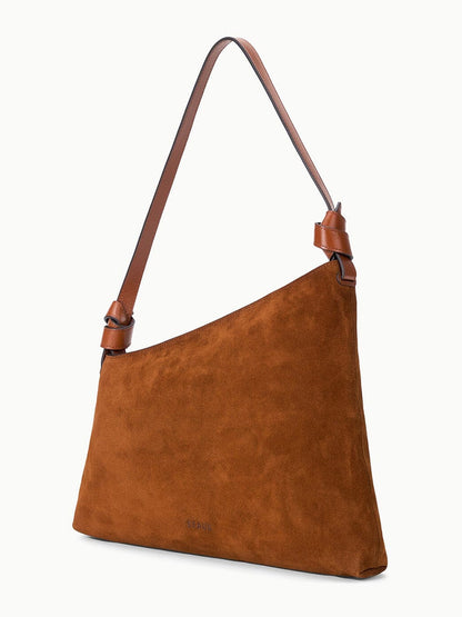 STAUD Dani Shoulder Bag in Tabac, crafted from brown suede with a single adjustable leather strap and featuring an elegant asymmetrical silhouette, photographed against a plain white background.