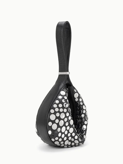 The STAUD Demy Shoulder Bag in Rivets is a black, teardrop-shaped shoulder bag with a looped handle and large white polka dots, crafted from soft nappa leather.