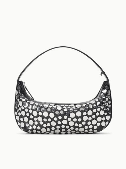 The STAUD Demy Shoulder Bag in Rivets is a black nappa leather handbag with a single strap, adorned with large, irregular white polka dots for a playful touch.
