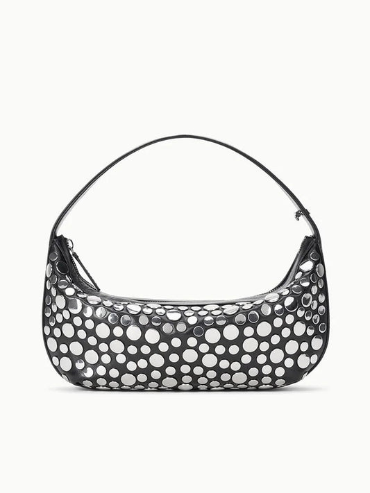 The STAUD Demy Shoulder Bag in Rivets is a black nappa leather handbag with a single strap, adorned with large, irregular white polka dots for a playful touch.
