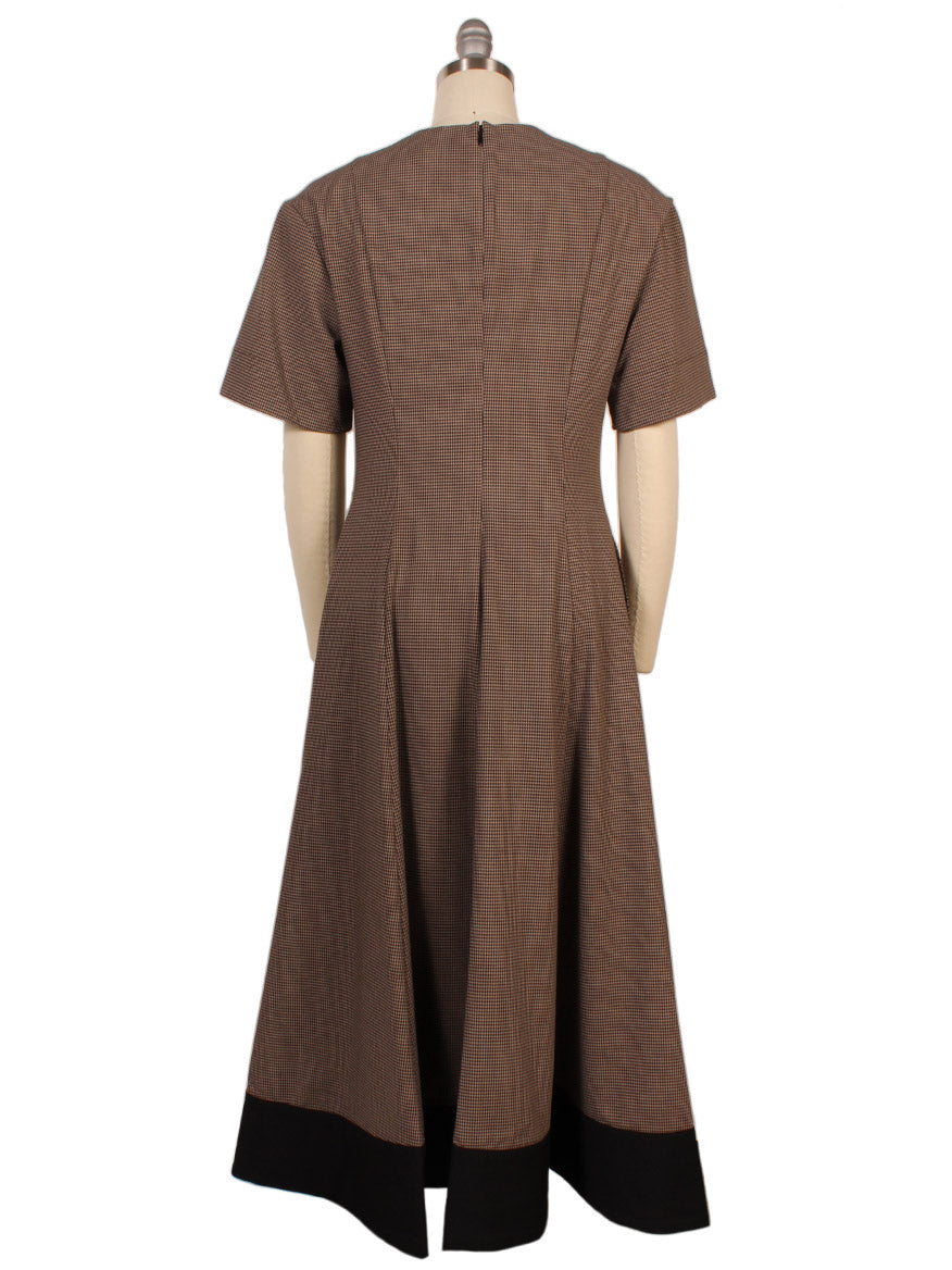 The STAUD Frances Short Sleeve Dress in Houndstooth features a split neck, fitted waist, A-line skirt, black hem, short sleeves, and a back zipper, shown here on a dress form.
