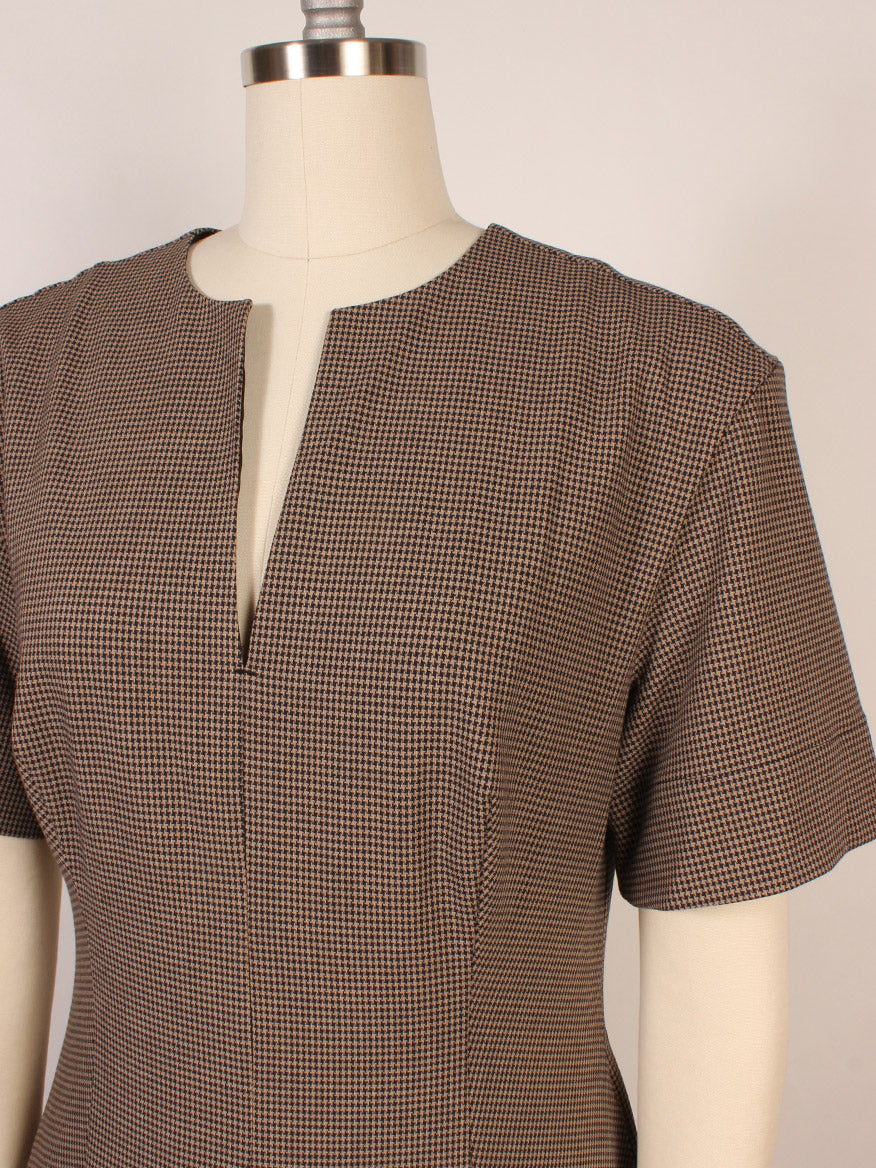 A close-up of a mannequin wearing the STAUD Frances Short Sleeve Dress in houndstooth cotton poplin, featuring short sleeves, an A-line skirt, and a front notch neckline.