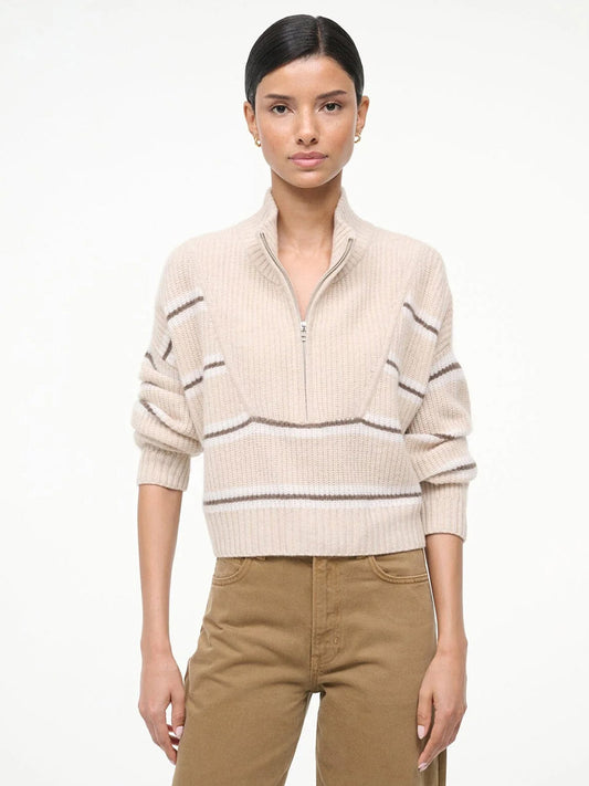 A woman faces forward against a white background, wearing the STAUD Hampton Cropped Cashmere Sweater in Whisper Stripe and brown pants.