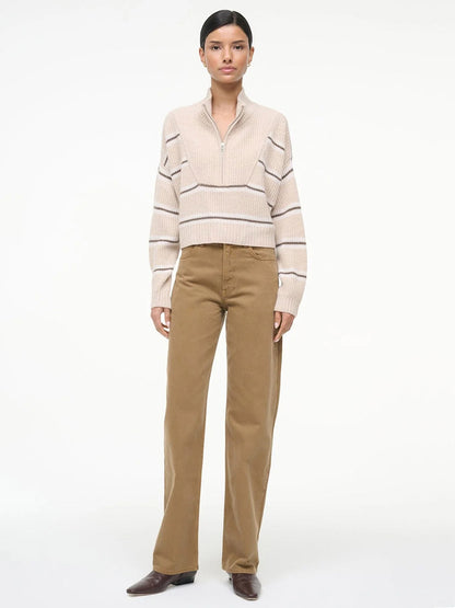 A person stands against a plain background wearing the STAUD Hampton Cropped Cashmere Sweater in Whisper Stripe, paired with tan wide-leg pants and brown shoes.