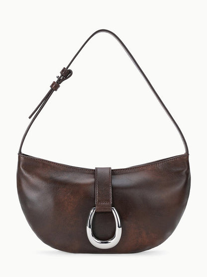 The STAUD Harlow Crescent Shoulder Bag in Espresso Distressed features rich distressed leather in deep brown, accented by a single strap and a metallic moon buckle on its minimalist front flap for enduring appeal.