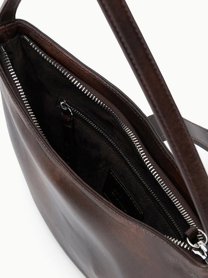 Close-up of the STAUD Harlow Crescent Shoulder Bag in Espresso Distressed leather, featuring a sleek open design that reveals a visible zippered inner pocket and dark fabric lining.