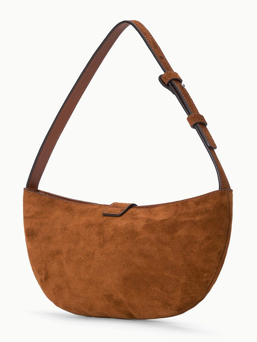 The STAUD Harlow Crescent Shoulder Bag in Tabac features brown suede in a semicircular shape, equipped with an adjustable dark brown strap and finished with a signature moon buckle, showcased against a plain white background.