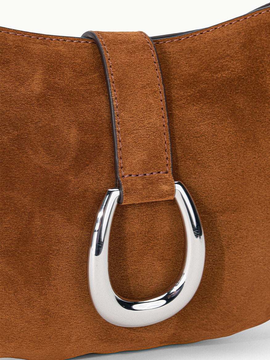 Close-up of the STAUD Harlow Crescent Shoulder Bag in Tabac, showcasing its wide strap and prominent oval-shaped silver moon buckle.