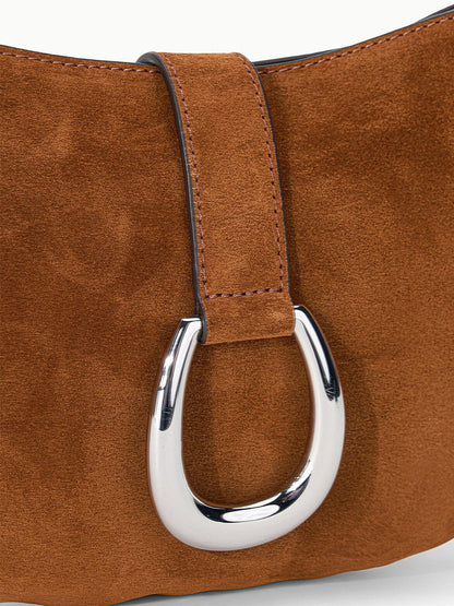 Close-up of the STAUD Harlow Crescent Shoulder Bag in Tabac, showcasing its wide strap and prominent oval-shaped silver moon buckle.