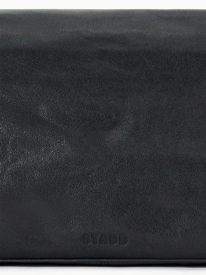 Close-up of the smooth black leather surface of the STAUD Harlow Medium Bag in Black, featuring the embossed "STAUD" logo at the bottom center.