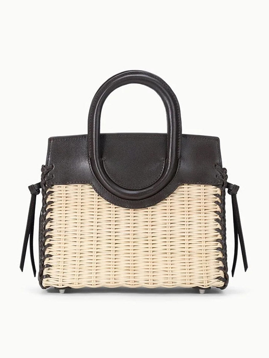 The STAUD Maude Mini Wicker Carryall in Natural/Espresso features a woven beige wicker body with espresso leather top, handles, and side ties, showcased elegantly against a plain white background.