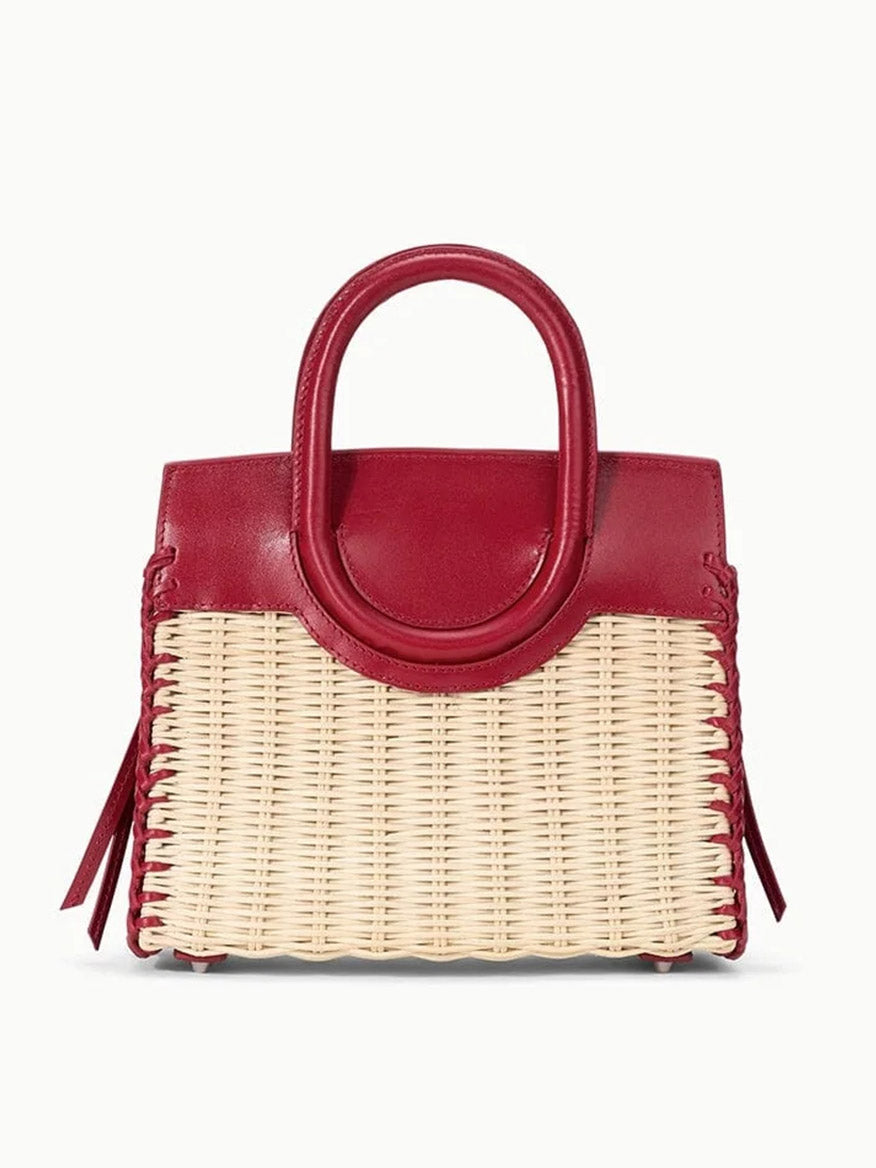 The STAUD Maude Mini Wicker Carryall in Natural/Rouge features a woven straw body with red leather handles and trim, displayed against a plain background.