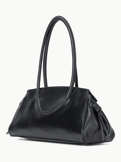 The STAUD Maude Shoulder Bag in Black features polished leather, double loop handles, a side knot detail, and an elegant east-west silhouette, shown against a plain white background.