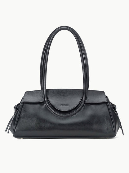 The STAUD Maude Shoulder Bag in Black is crafted from polished leather with double rounded handles and a flap closure, showcasing an elegant east-west silhouette against a plain white background.