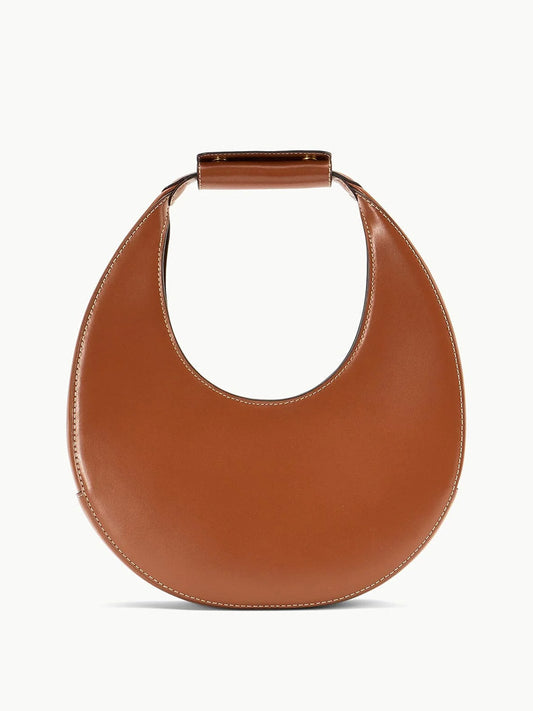 Tan leather crescent moon-shaped tote with a structured handle and suede lining, ideal for any occasion, known as the STAUD Moon Tote Bag.