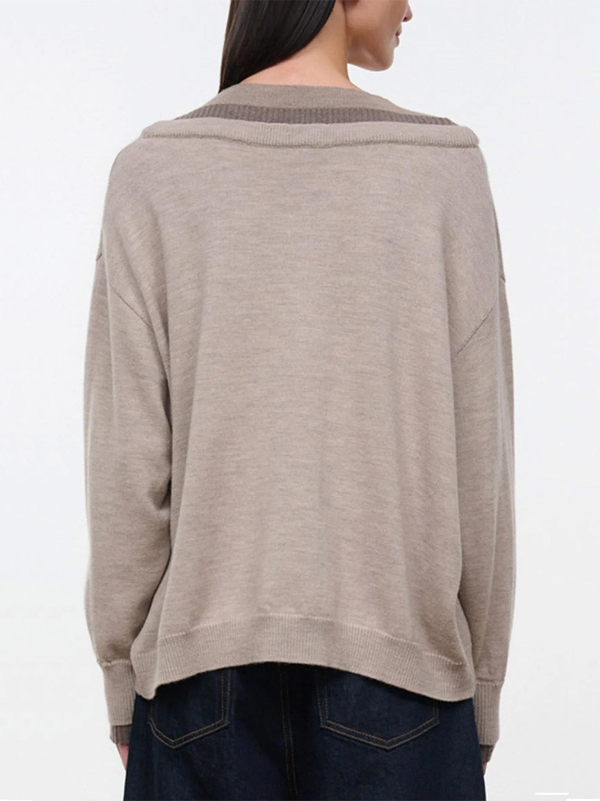 Back view of a person wearing the STAUD Norman Sweater in Sesame Multi, an oversized, beige knit sweater with a wide, ribbed triple-layer neckline that rests off the shoulders.