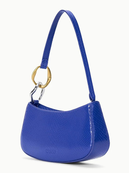 The STAUD Ollie Bag in Cobalt is a small blue snake-print leather mini shoulder bag with a short strap and large gold ring detail, shown against a plain white background.