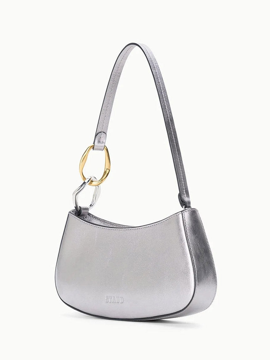 The STAUD Ollie Bag in Pewter is a metallic leather mini shoulder bag with gold and silver two-tone hardware ring detail on the strap and "STAUD" embossed on the front.