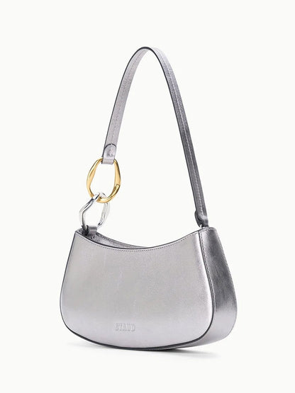 The STAUD Ollie Bag in Pewter is a metallic leather mini shoulder bag with gold and silver two-tone hardware ring detail on the strap and "STAUD" embossed on the front.