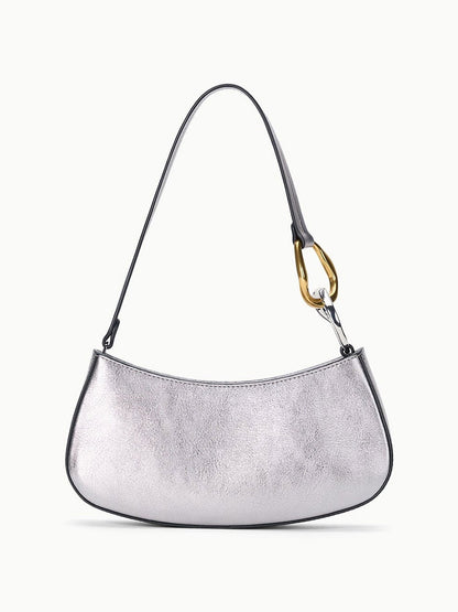 The STAUD Ollie Bag in Pewter is a silver, crescent-shaped mini shoulder bag with a single strap and eye-catching two-tone hardware, including a gold-tone metal accent on one side.