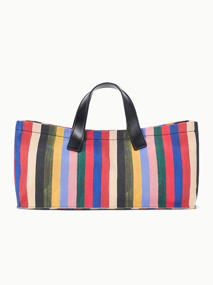 The STAUD Port Tote in Artist Stripe features leather handles and vertical multicolored stripes in yellow, red, blue, green, black, and pink.