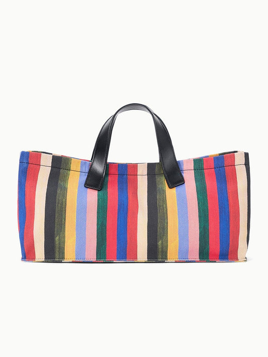 The STAUD Port Tote in Artist Stripe features leather handles and vertical multicolored stripes in yellow, red, blue, green, black, and pink.