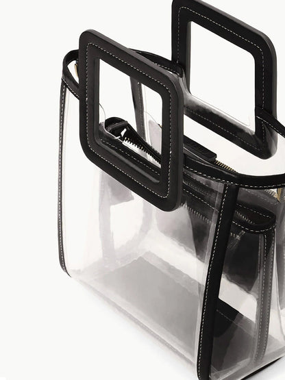 The STAUD Stadium Mini Shirley Bag in Clear/Black features clear PVC, black trim, square handles, and white stitching with a visible inner zip pouch—stylish, stadium-approved, and perfect for events.