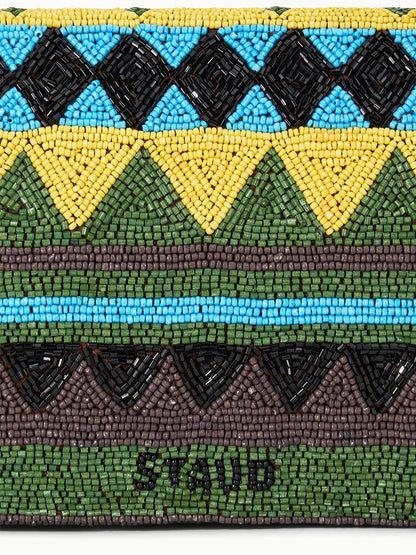 A close-up of the STAUD Timmy Shoulder Bag in Happy Sack, showcasing beaded geometric patterns in black, yellow, green, brown, and blue, with "STAUD" spelled out in black beads at the bottom.