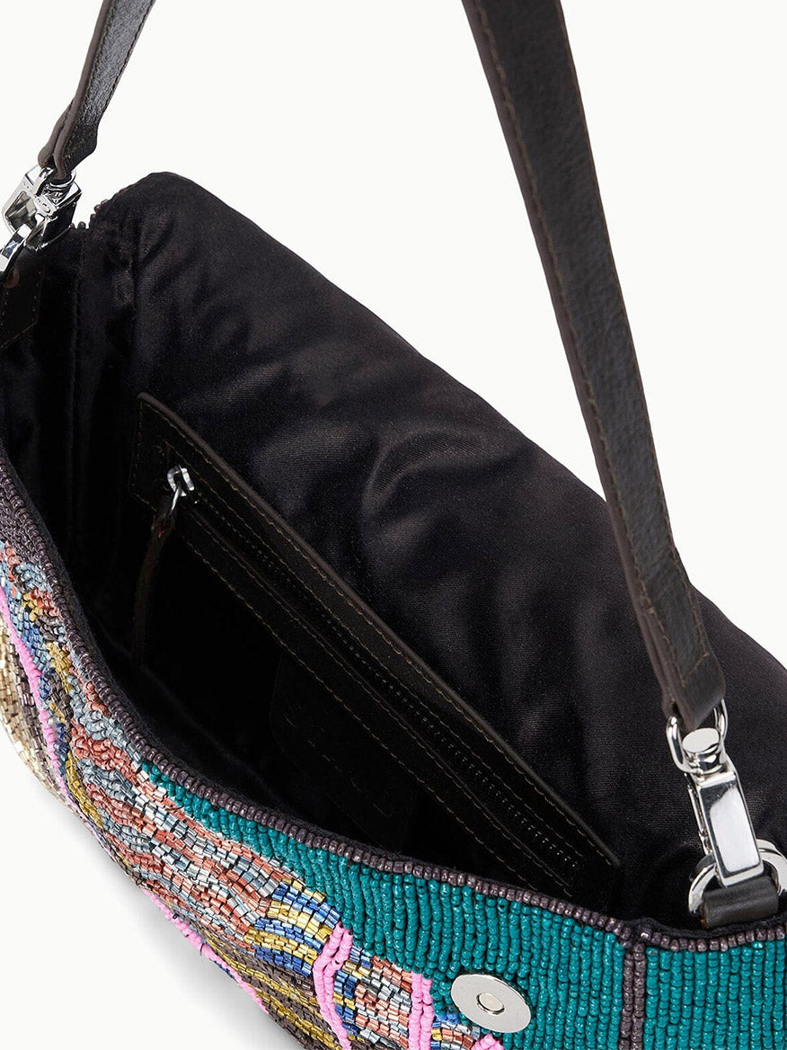 Close-up of the STAUD Timmy Shoulder Bag in Conch Shell featuring an open beaded design, black fabric interior, inner pocket, magnetic closure, and a dark shoulder strap.
