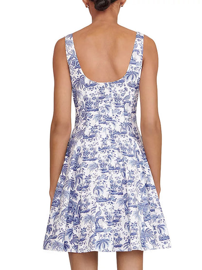 A woman is shown from the back wearing the STAUD Wells Mini Sleeveless Dress in China Blue Toile, featuring white cotton poplin with a blue toile pattern and a scoop back.