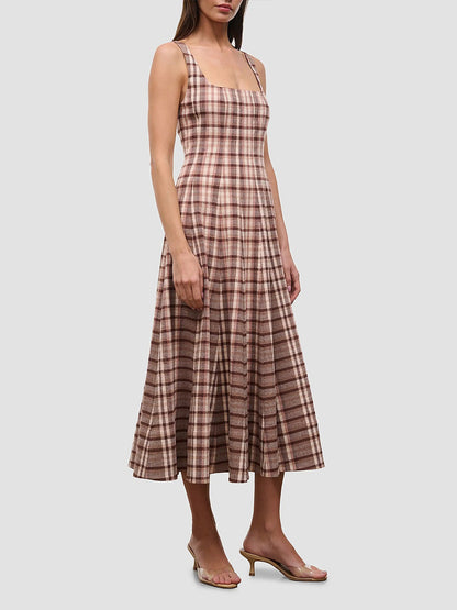 A woman wearing the STAUD Wells Sleeveless Dress in Tuscany Plaid—an ankle-length cotton poplin dress featuring a square neckline and a fitted bodice—paired with clear heeled sandals.