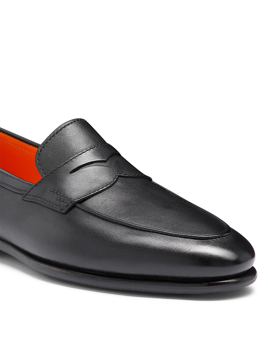 The Santoni Carlos Black Leather Penny Loafer features premium-quality black leather and an orange inner lining, displayed from a side angle.