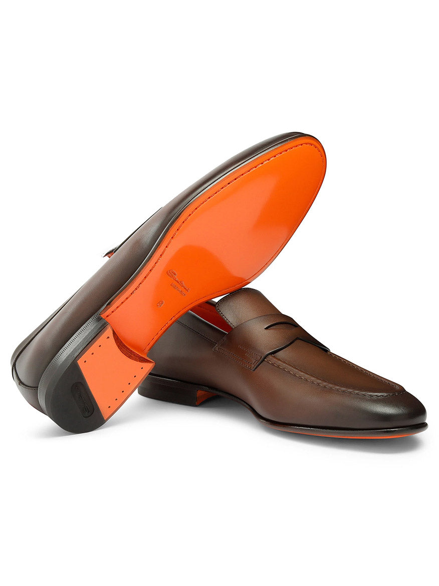 The Santoni Edvin Leather Loafers in brown feature distinctive orange soles, one shoe displayed on its side and the other upright, highlighting their artisanal craftsmanship.