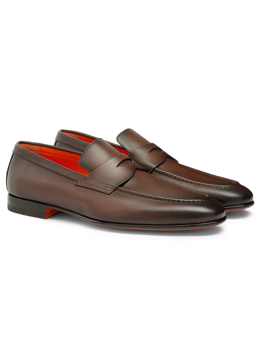 The Santoni Edvin Leather Loafer in brown showcases a sleek design with artisanal craftsmanship, featuring a stylish strap and red interior lining.