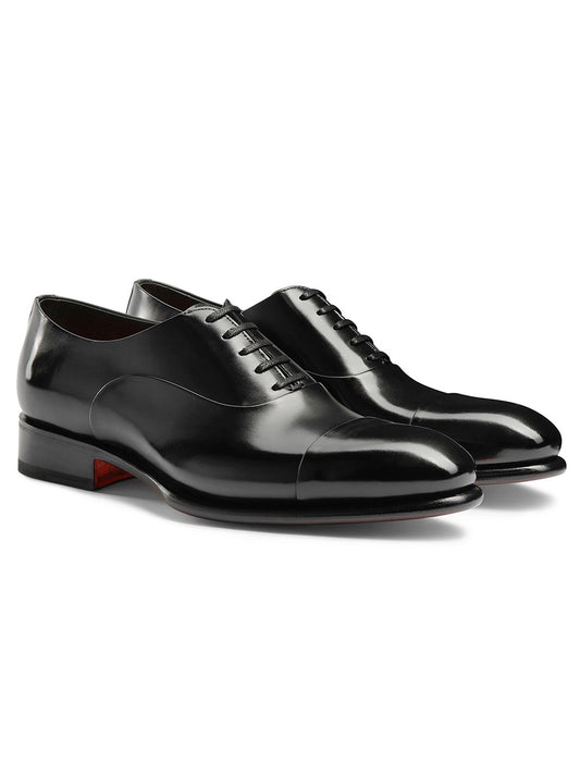 The Santoni Isaac Balmoral Oxford in black is a polished leather dress shoe featuring high-quality craftsmanship, laces, and a low heel, showcased on a white background.