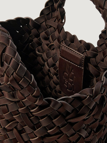 Close-up of a dark brown Naghedi St. Barths Petit Tote Nest Weave in Chocolate, a handwoven neoprene bag featuring an interior leather patch with an embossed logo.