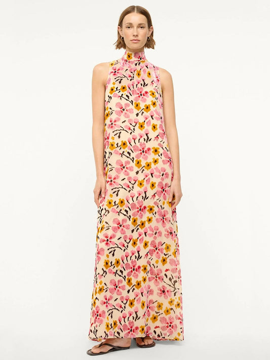 A person in the STAUD Albee Dress, featuring a velvet burnout design with a floral pattern and high neckline, stands elegantly against a plain background.