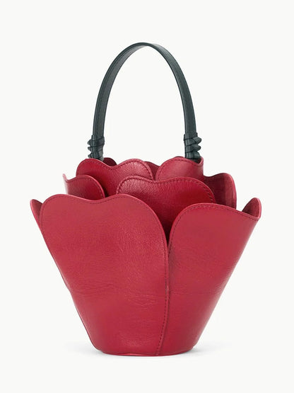 Introducing the STAUD Juliet Bag in Rouge: a striking novelty accessory shaped like delicate petals. This red, flower-inspired leather handbag features a black handle, blending elegance and creativity as the perfect handheld bag.