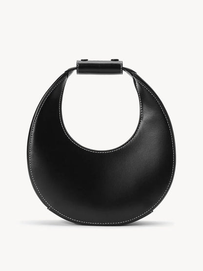 The STAUD Mini Moon Bag in Black is a leather crescent bag with white stitching, a rounded body, and a short, wide top handle.