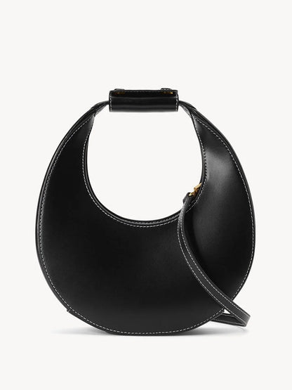 The STAUD Mini Moon Bag in Black features a crescent-shaped leather design with a short stitched handle and thin crossbody strap, shown against a plain white background.