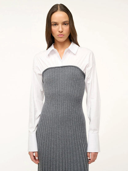 A woman with long brown hair is wearing the STAUD O'Keefe Pleated Dress in Charcoal/White, standing against a plain white background.