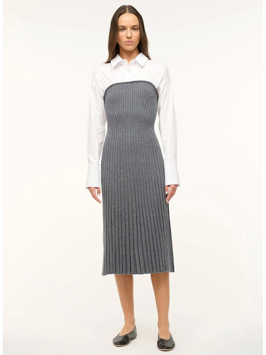 A woman stands against a plain background wearing the STAUD O'Keefe Pleated Dress in Charcoal/White, paired with a white cotton poplin shirt and black flats.