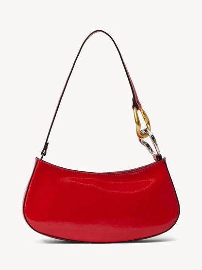 The STAUD Ollie Bag in Cherry is a red polished leather mini shoulder bag with a curved shape and a single strap featuring gold and silver chain links on one side.