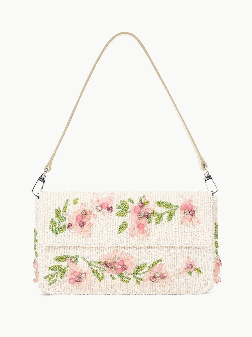 The STAUD Timmy Shoulder Bag in Magnolia combines style and functionality with its beige design, pink floral embroidery, green leaves, removable leather strap, and convenient magnetic closure.