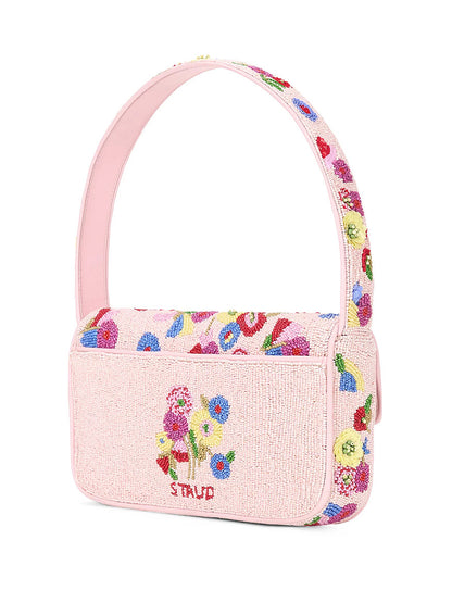 The STAUD Tommy Beaded Bag in Wildflowers is a pink floral hand-beaded shoulder bag, showcasing the brand name "STAUD" embroidered on the front. Its elegant strap and intricately embellished 3D flowers make it a standout accessory for any occasion.