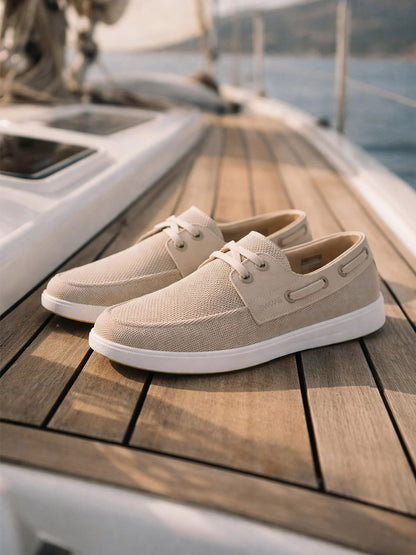 The Swims Breeze Boat Shoe in Mist/Sand features lightweight comfort and white soles, perfect for relaxing on a sailboat's wooden deck.
