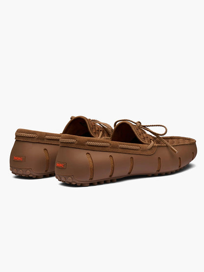 The Swims Woven Driver in Nut is a brown, water-friendly moccasin-style loafer with rubber pebble soles and laces, shown from the back and side on a white background. Stylish, comfortable, and perfect for versatile wear.